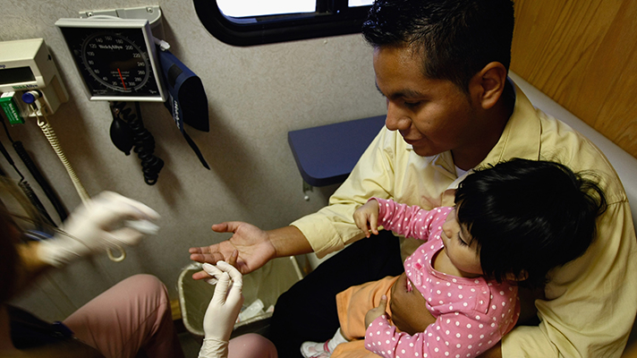 A child of a Mexican immigrant receives free health checkups at a mobile clinic