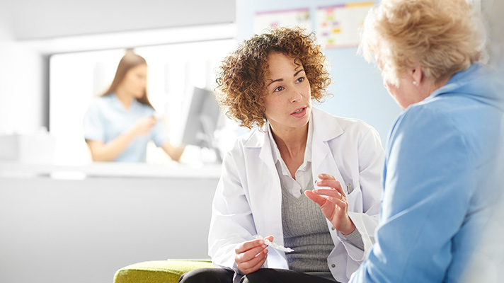 A patient speaks with a doctor in a hospital setting