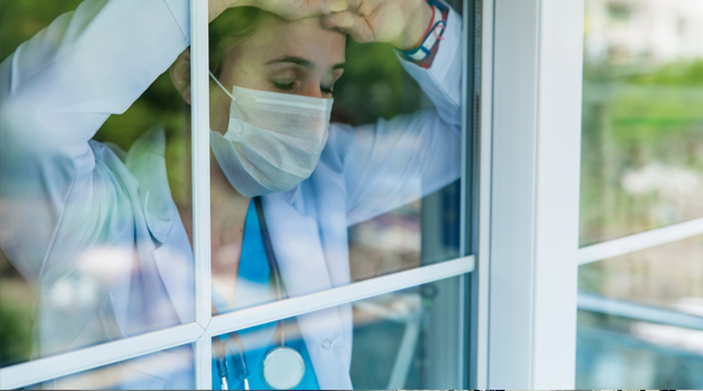 Doctor with mask looking out of a window