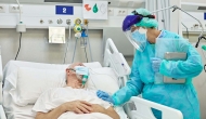 Person wearing PPE at hospital bed