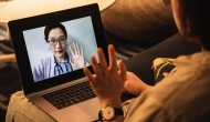 Telehealth visit as person waves to professional on laptop screen