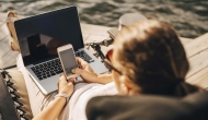 Physician on beach working on laptop and phone