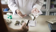 Person in lab coat showing person bags of cannabis