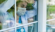 Doctor with mask looking out of a window